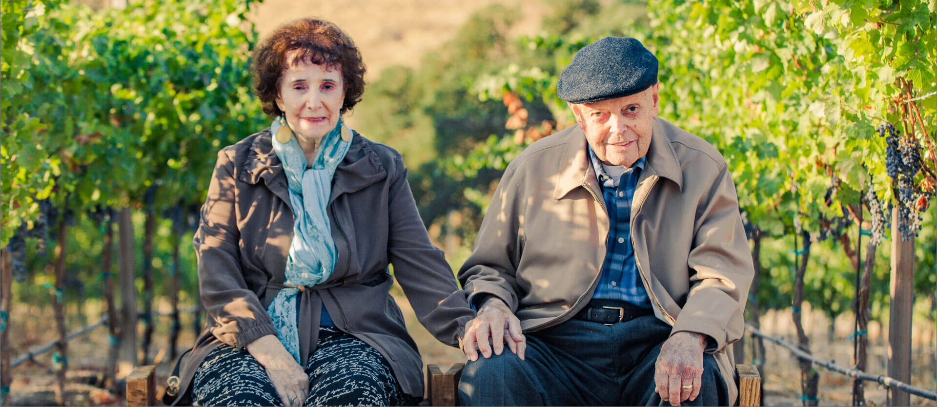 Stefano and Maddalena Riboli sitting on a bench in the vineyard